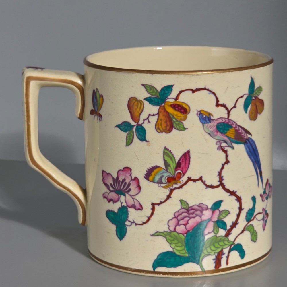 A large cream porcelain mug decorated with hand-painted polychrome birds, insects, flowers, and a gilded rim. View X
