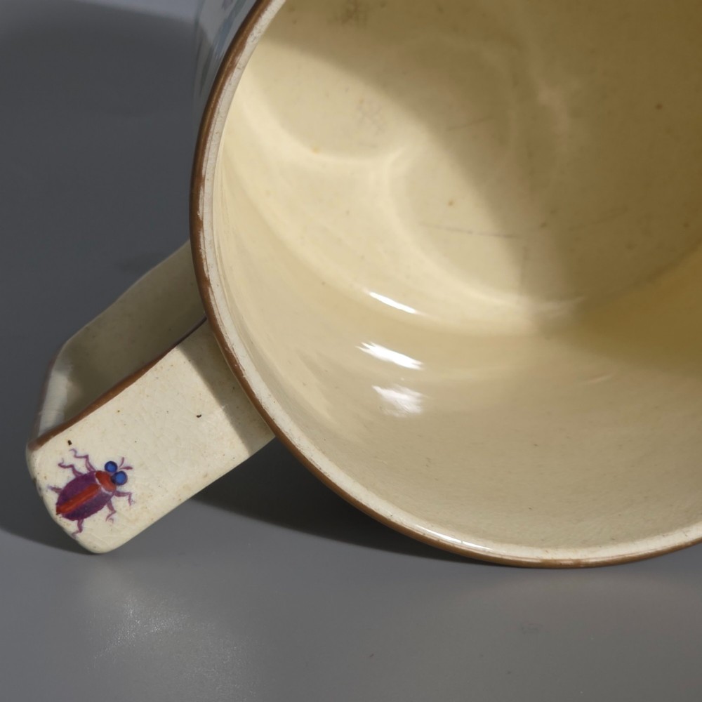 A large cream porcelain mug decorated with hand-painted polychrome birds, insects, flowers, and a gilded rim. View XI