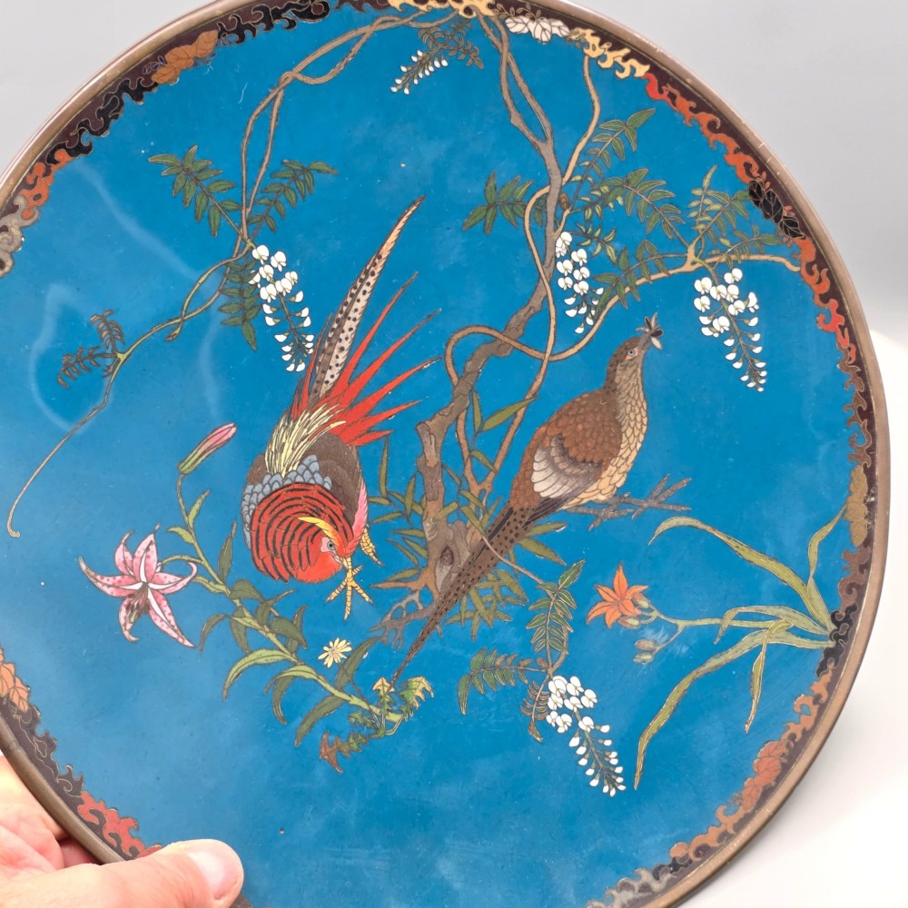 A circular Japanese Meiji period cloisonne enamel charger depicting birds perched on branches with flowers against a bright blue background. View IV