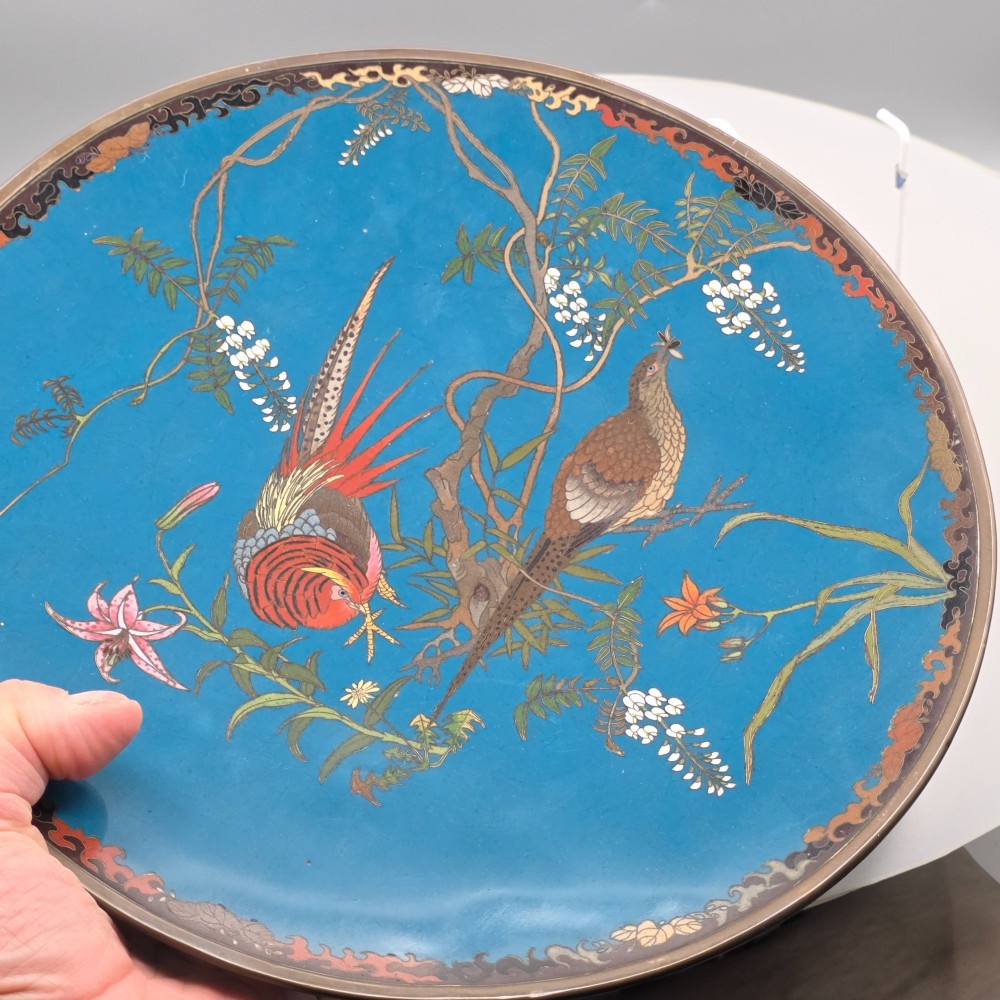A circular Japanese Meiji period cloisonne enamel charger depicting birds perched on branches with flowers against a bright blue background. View V