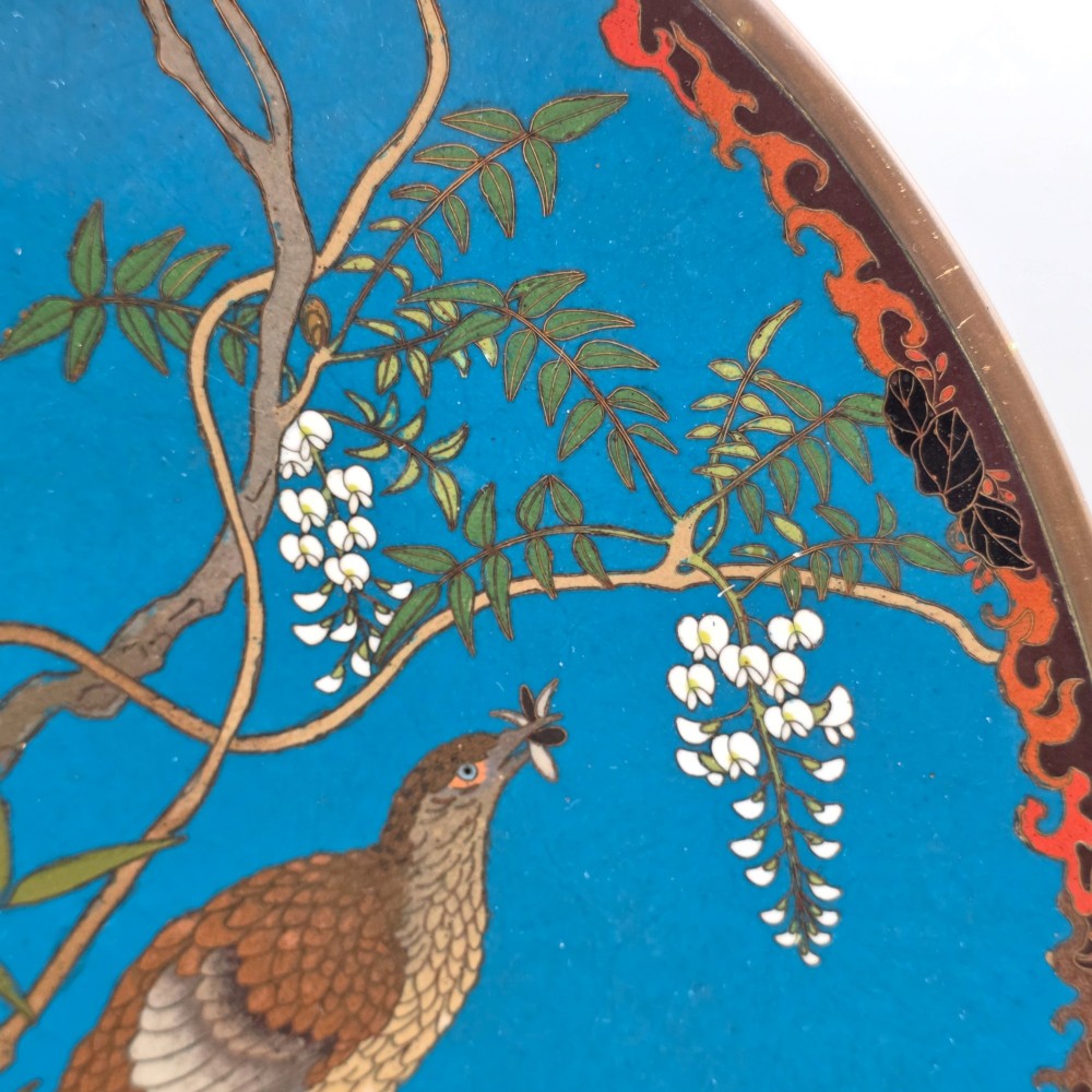 A circular Japanese Meiji period cloisonne enamel charger depicting birds perched on branches with flowers against a bright blue background. View VIII