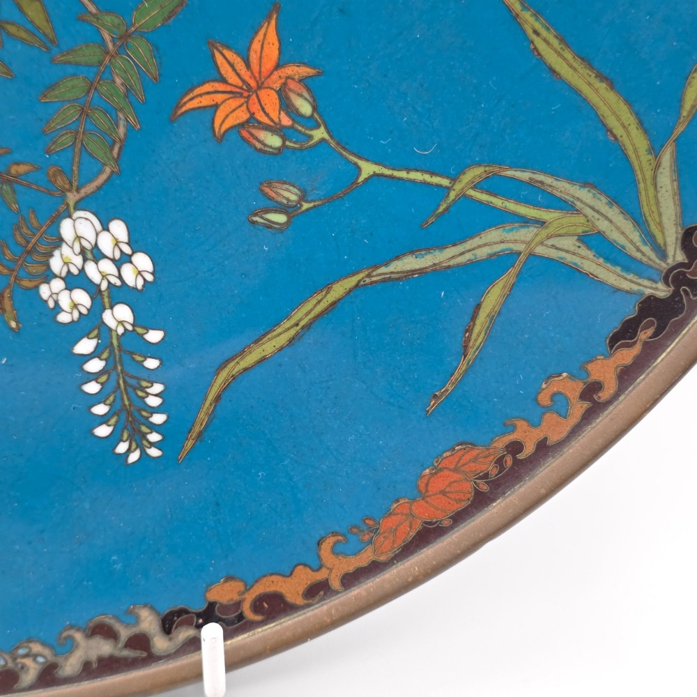 A circular Japanese Meiji period cloisonne enamel charger depicting birds perched on branches with flowers against a bright blue background. View IX
