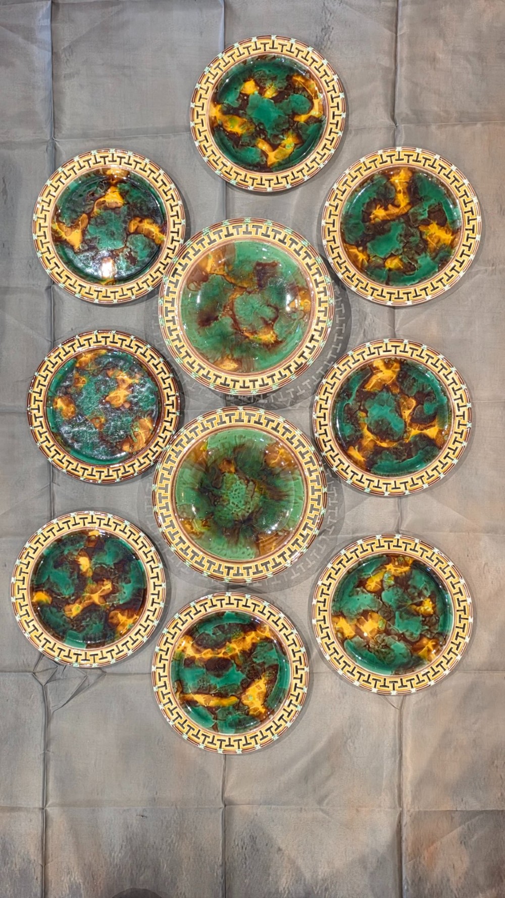 A ten-piece nineteenth-century Wedgwood majolica dessert service featuring green and brown mottled glazes surrounded by classical Greek key pattern borders.