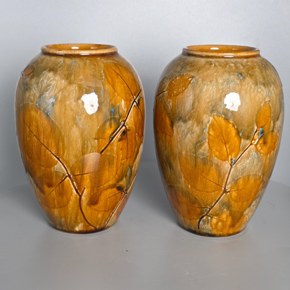 A pair of Edwardian baluster-shaped stoneware vases with warm ochre glaze and impressed leaf motifs.