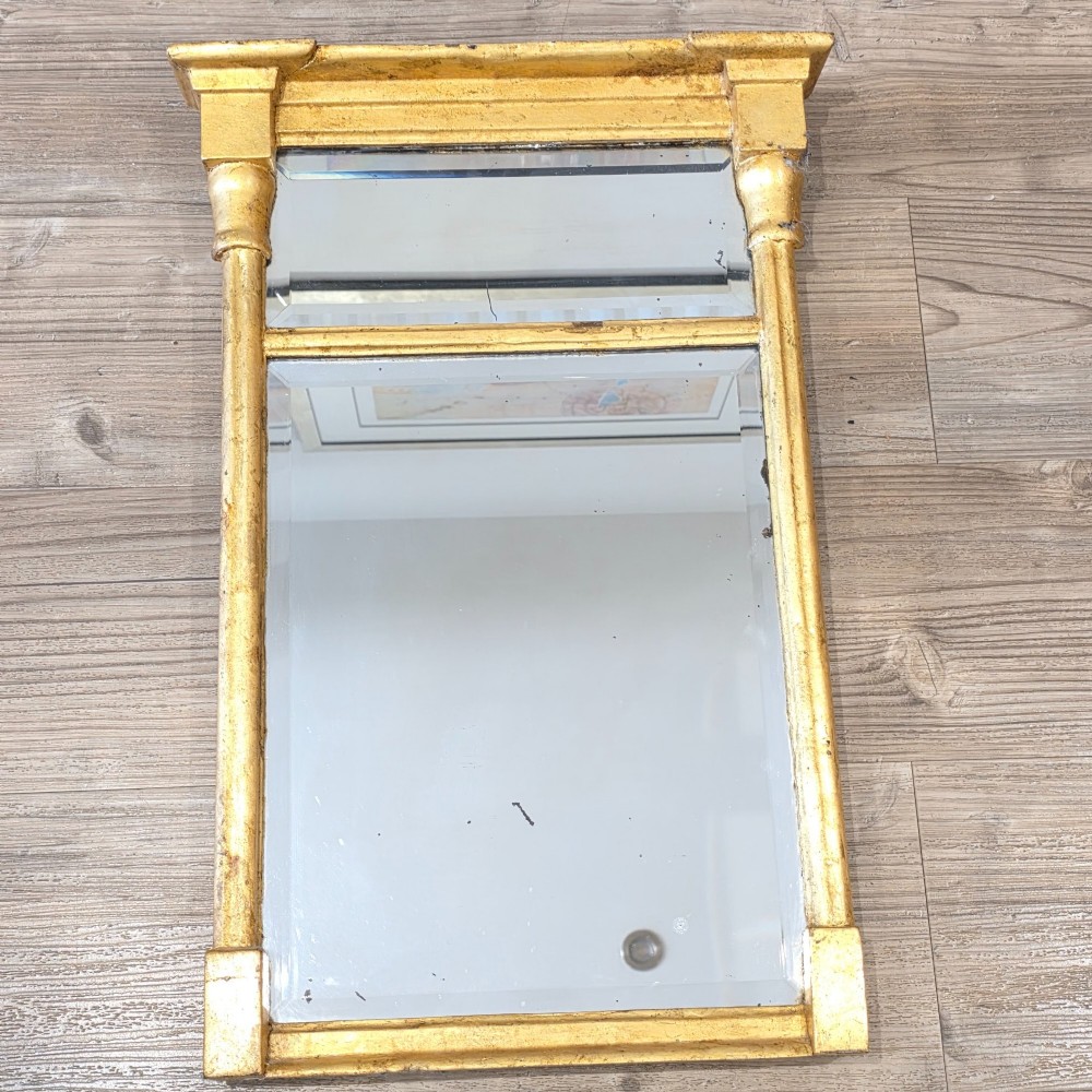 A rectangular Regency style giltwood pier mirror featuring side columns, an architectural cornice, and a two-section glass mirror plate.