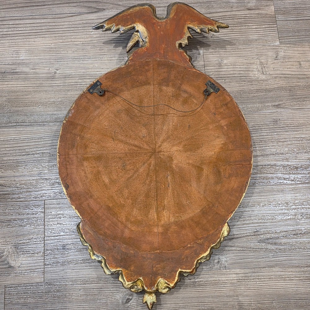 A circular convex mirror set in a gilded frame decorated with ball mouldings, an inner ebonised slip, topped with a carved eagle cresting. View VII