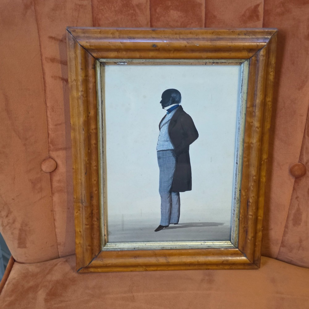 A framed full-length silhouette portrait of a gentleman in 19th-century costume presented in a birds eye maple frame. View II