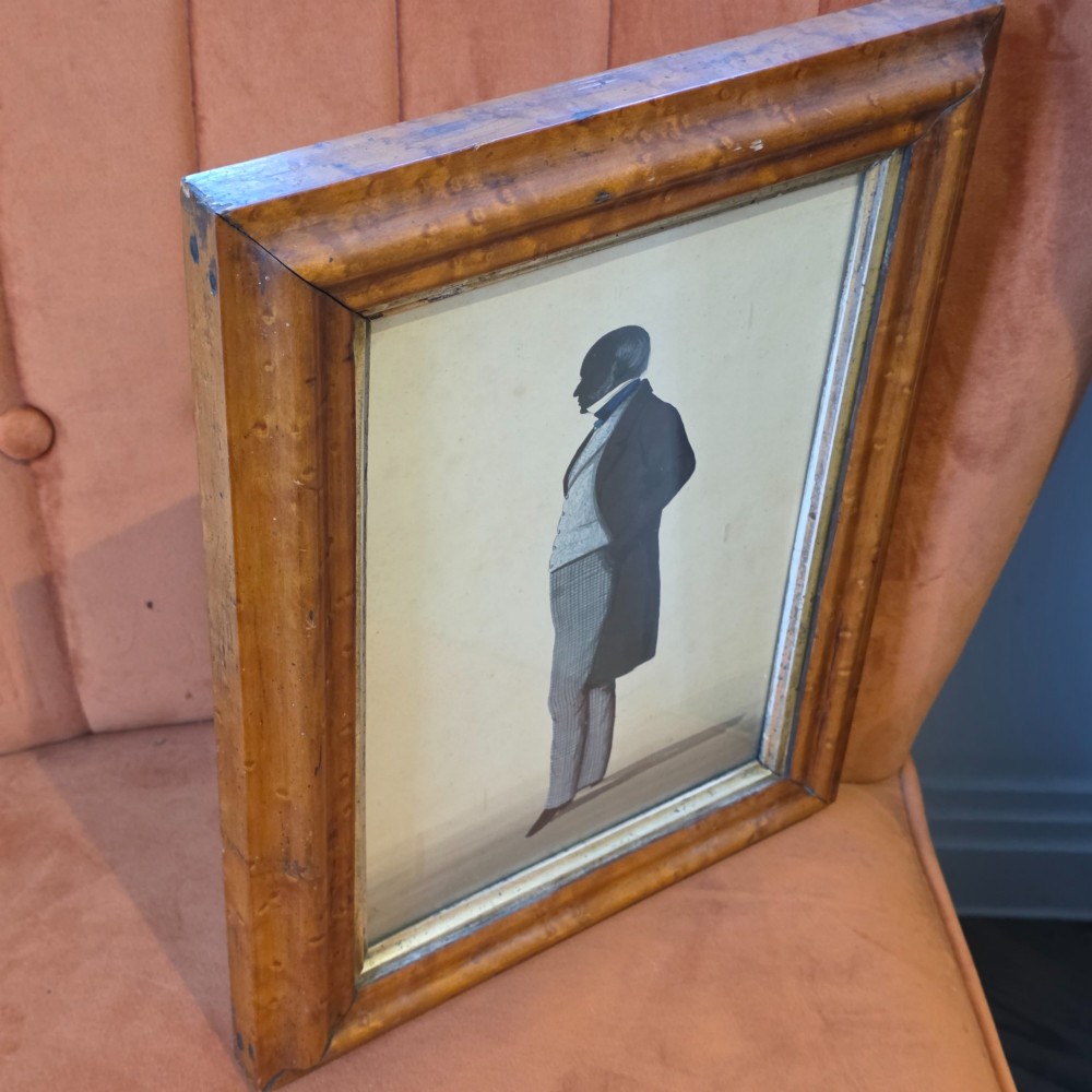 A framed full-length silhouette portrait of a gentleman in 19th-century costume presented in a birds eye maple frame. View VII