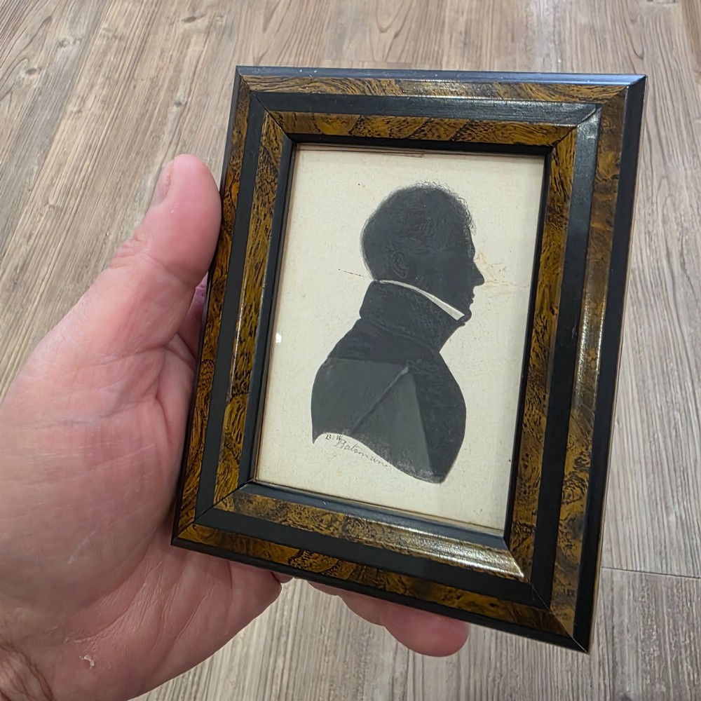 A small framed early 19th-century silhouette portrait depicting the right profile of a gentleman in a high-collared coat, presented in a decorated wood frame. View VI