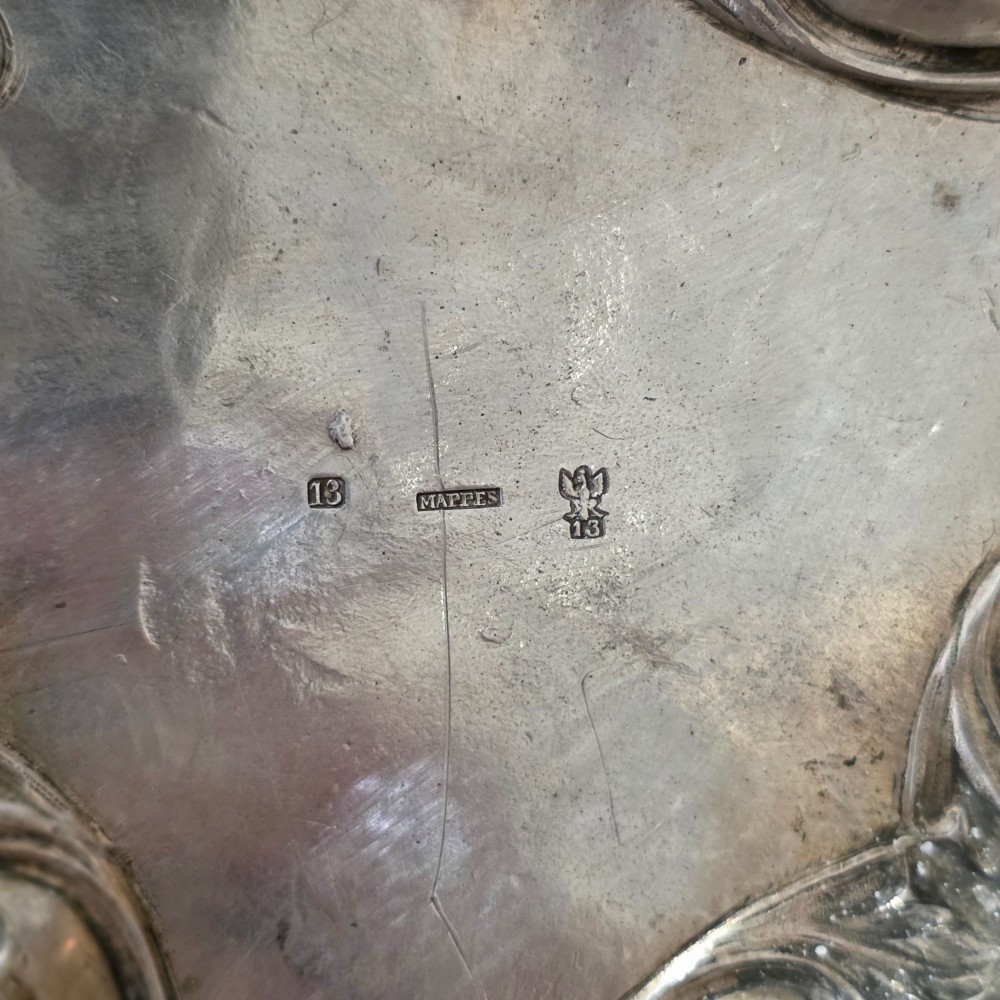 A set of four silver candlesticks with fluted columns and ornate leaf details set on molded tripod bases. View XV