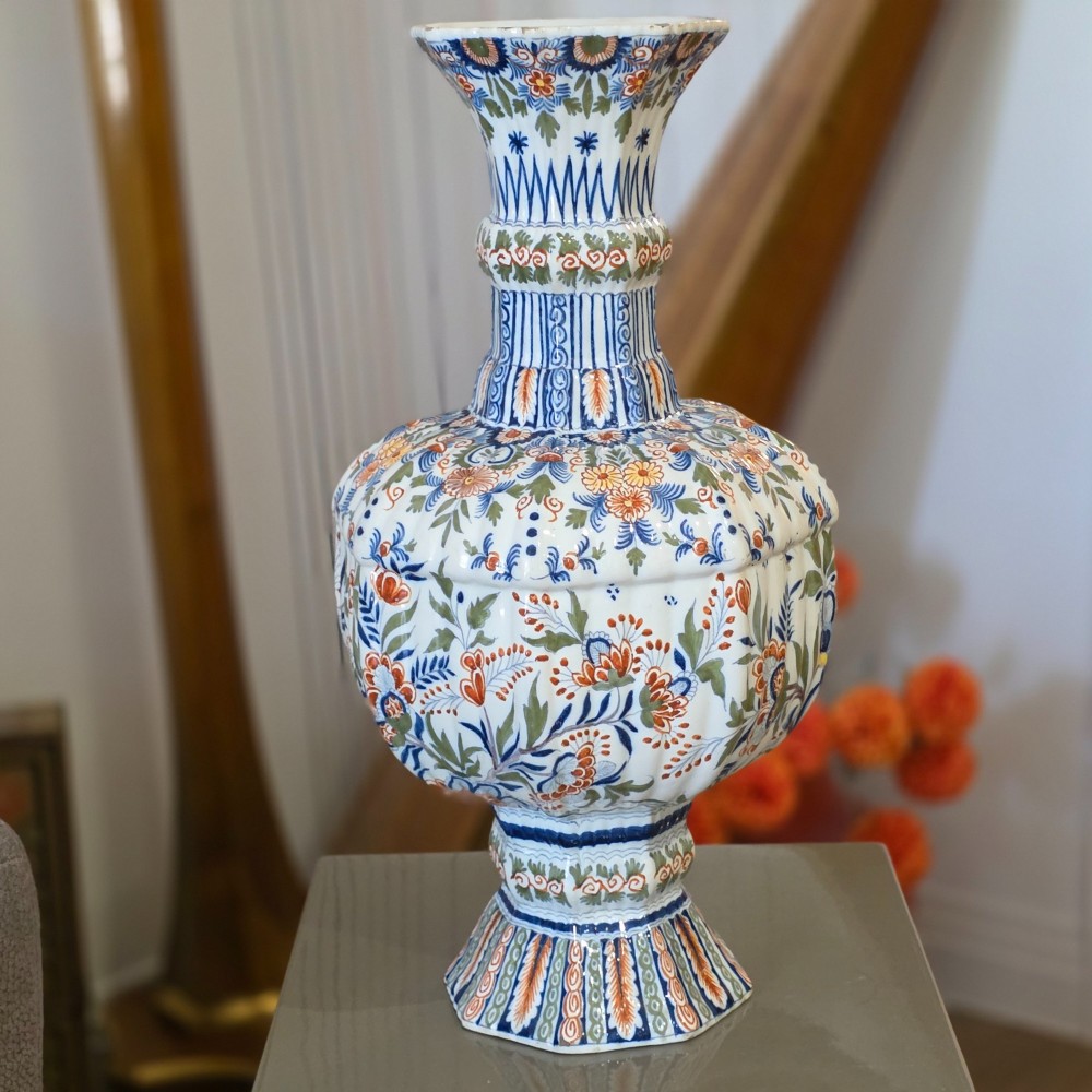 A tall nineteenth-century polychrome Delft earthenware vase featuring a fluted ribbed neck and bulbous body decorated with hand-painted floral motifs in blue, green, and orange on a white glazed ground. View II