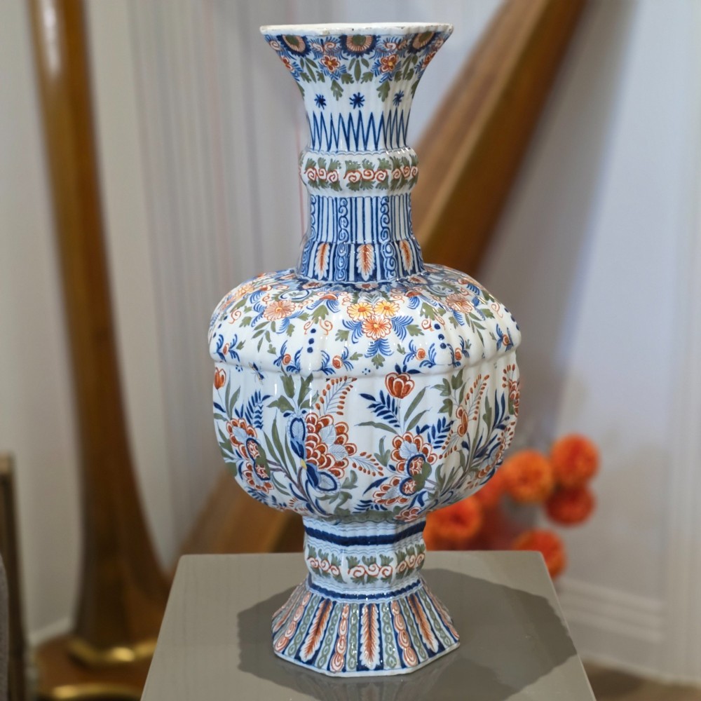 A tall nineteenth-century polychrome Delft earthenware vase featuring a fluted ribbed neck and bulbous body decorated with hand-painted floral motifs in blue, green, and orange on a white glazed ground. View III