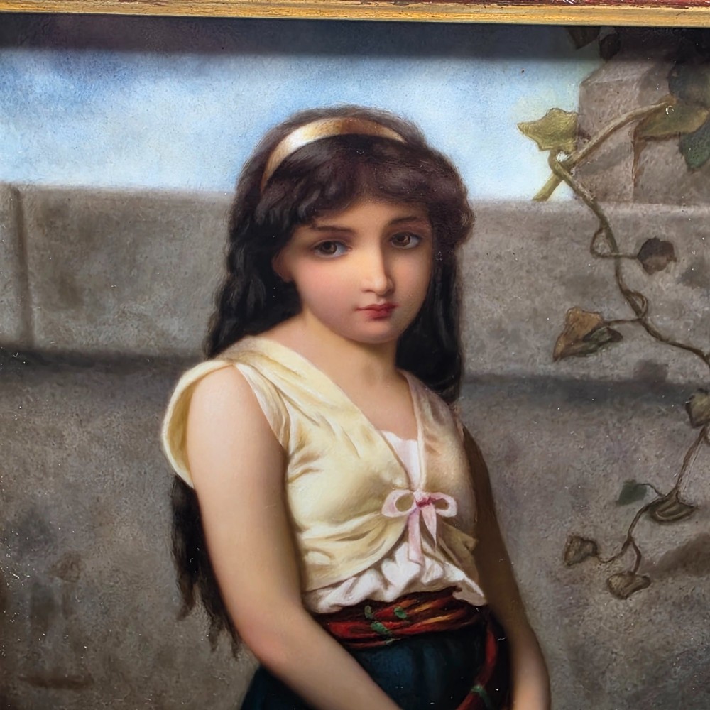 A rectangular hand-painted porcelain plaque depicting a young woman with a tambourine, set within a thick moulded gilt frame. View II