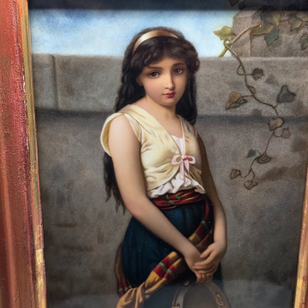 A rectangular hand-painted porcelain plaque depicting a young woman with a tambourine, set within a thick moulded gilt frame. View IV