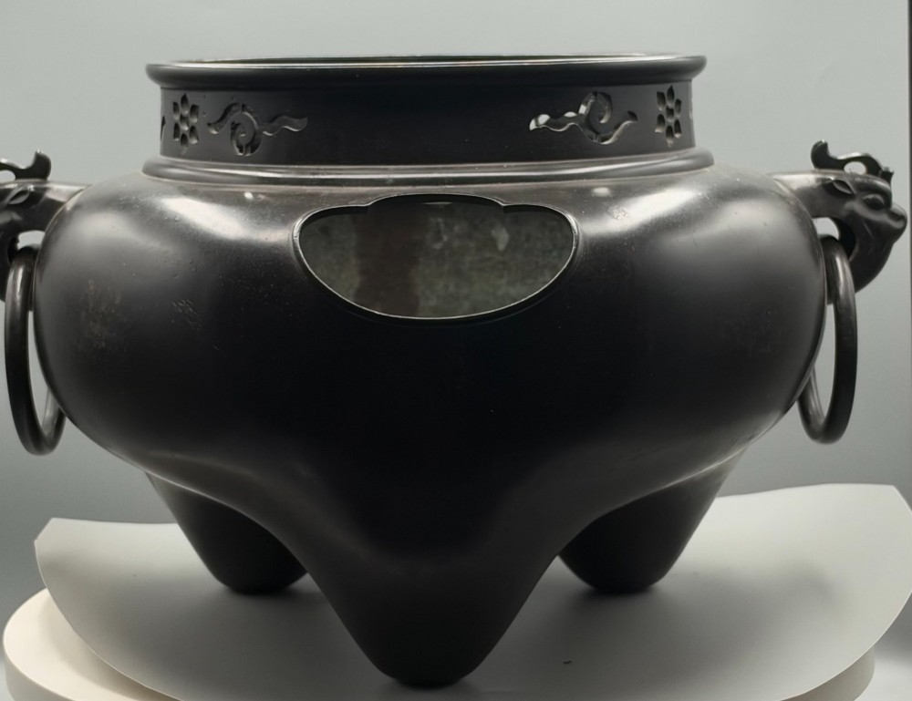 A dark patinated bronze tripod tea brazier featuring cast lion mask handles with loose ring pulls and pierced decorative motifs along the collar. View II