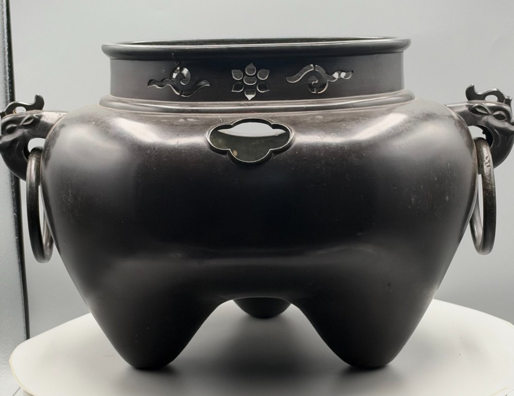 A dark patinated bronze tripod tea brazier featuring cast lion mask handles with loose ring pulls and pierced decorative motifs along the collar. View III