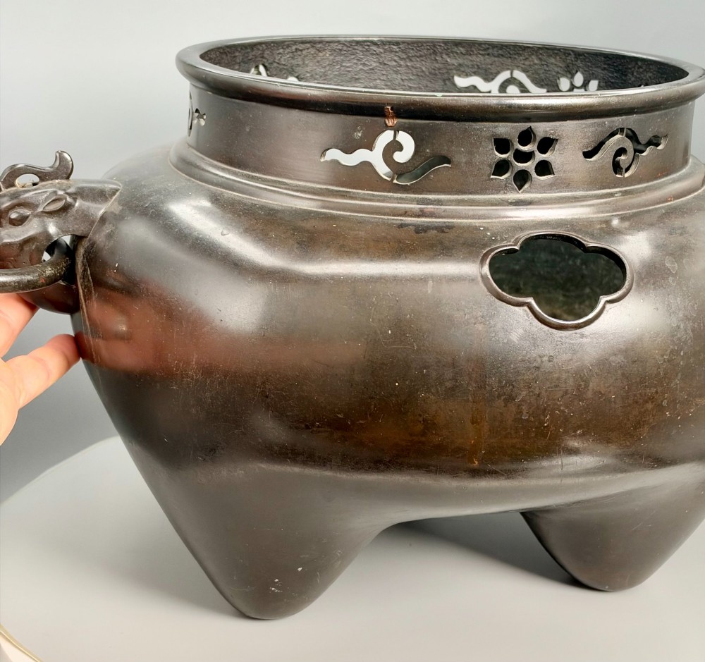 A dark patinated bronze tripod tea brazier featuring cast lion mask handles with loose ring pulls and pierced decorative motifs along the collar. View XIII