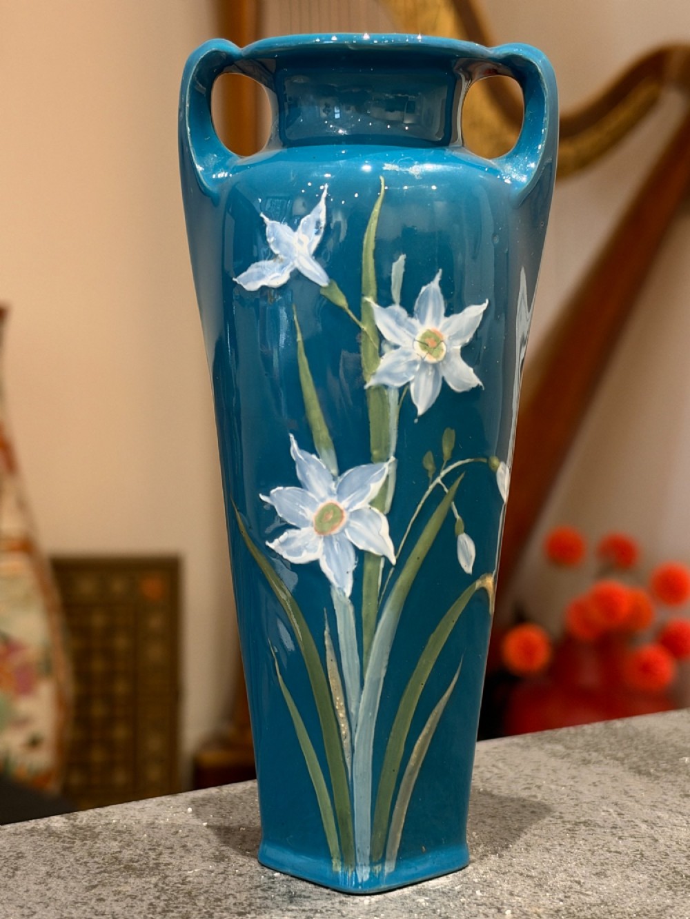 A tapered teal blue porcelain vase featuring twin loop handles and white pate-sur-pate floral relief decoration. View II