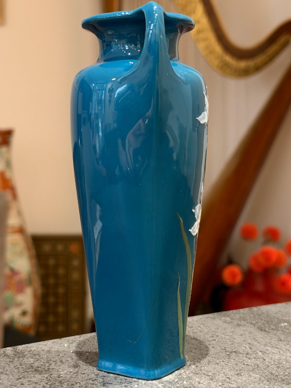A tapered teal blue porcelain vase featuring twin loop handles and white pate-sur-pate floral relief decoration. View III