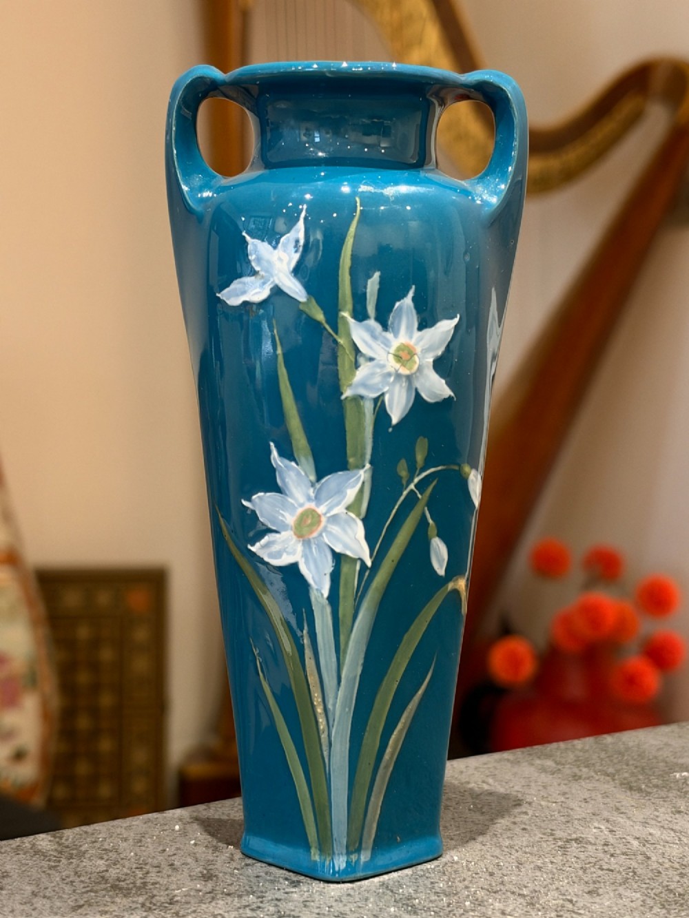 A tapered teal blue porcelain vase featuring twin loop handles and white pate-sur-pate floral relief decoration. View IV