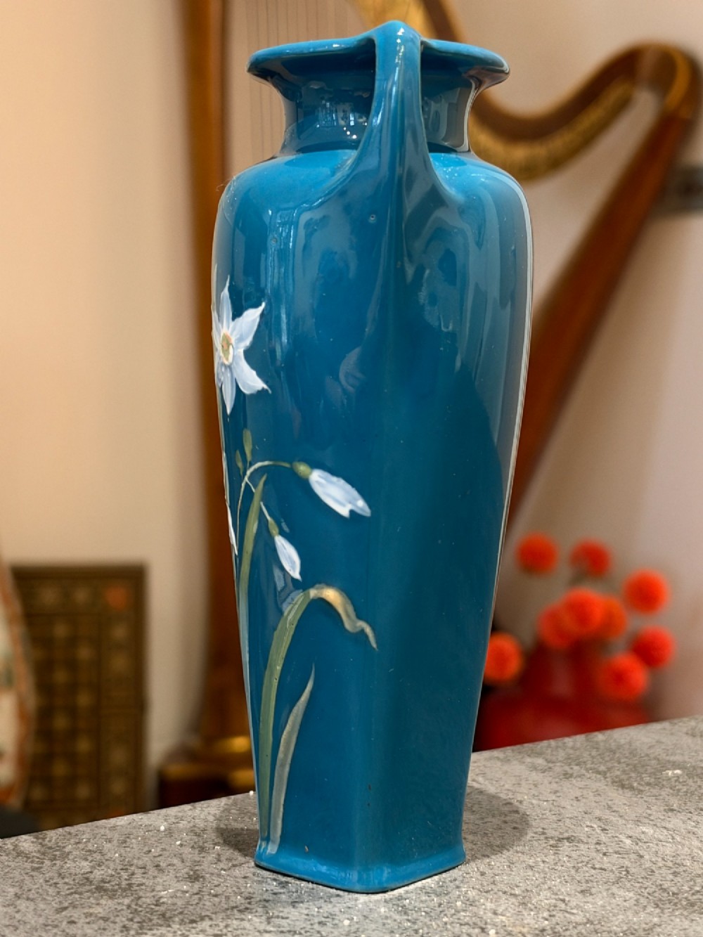 A tapered teal blue porcelain vase featuring twin loop handles and white pate-sur-pate floral relief decoration. View V