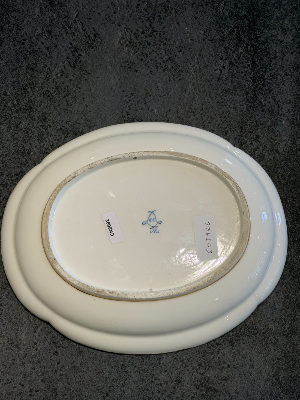 An oval French Sevres porcelain dish featuring a deep cobalt blue rim decorated with intricate gold leaf gilding surrounding a central hand-painted maritime harbour scene. View II