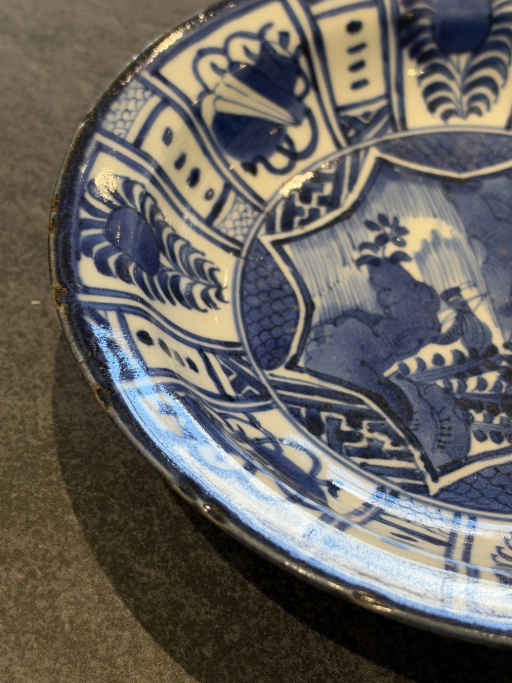A circular 17th-century Chinese Kraak porcelain dish featuring underglaze cobalt blue panelled decoration surrounding a central landscape reserve. View VII