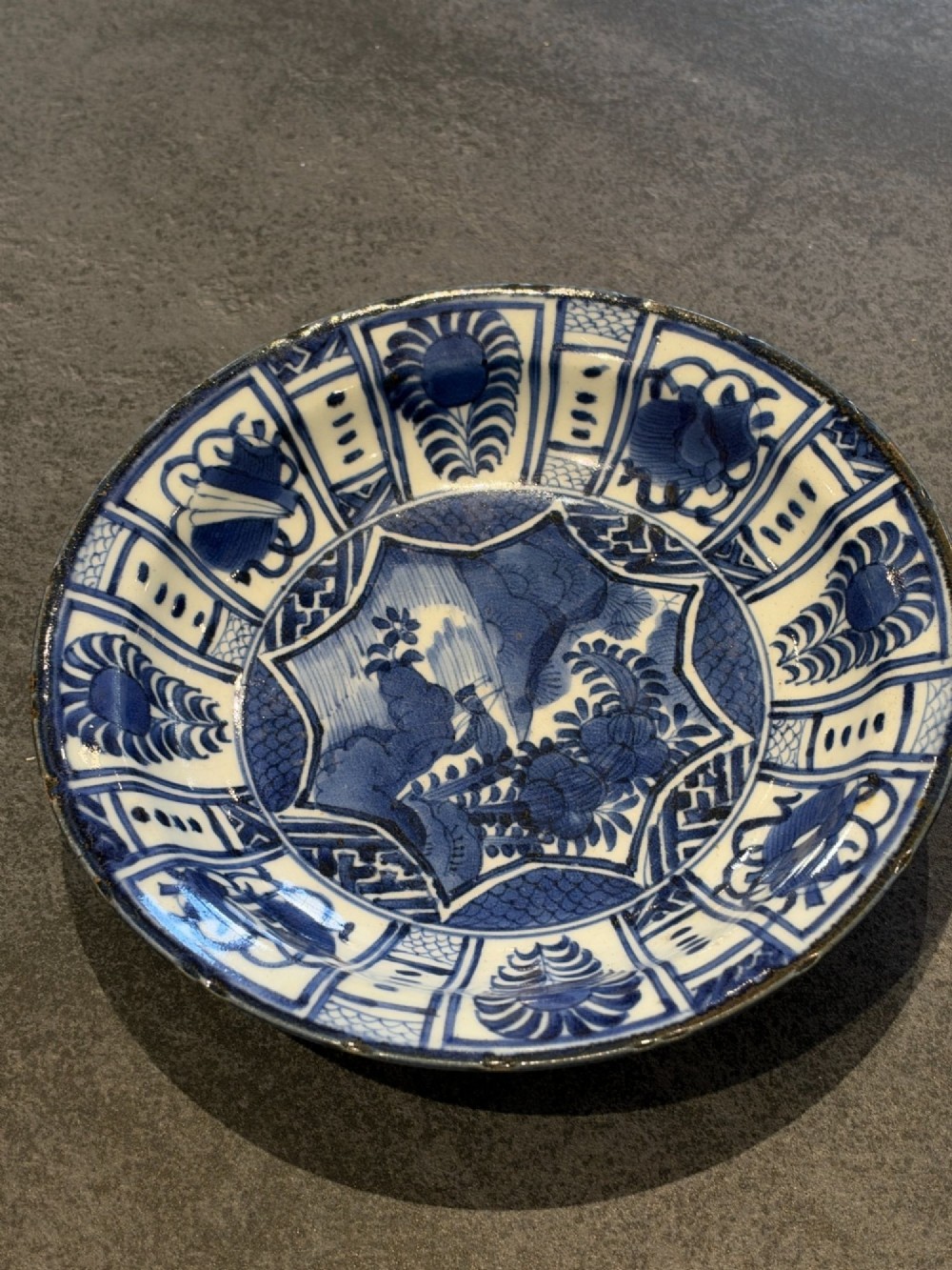 A circular 17th-century Chinese Kraak porcelain dish featuring underglaze cobalt blue panelled decoration surrounding a central landscape reserve.