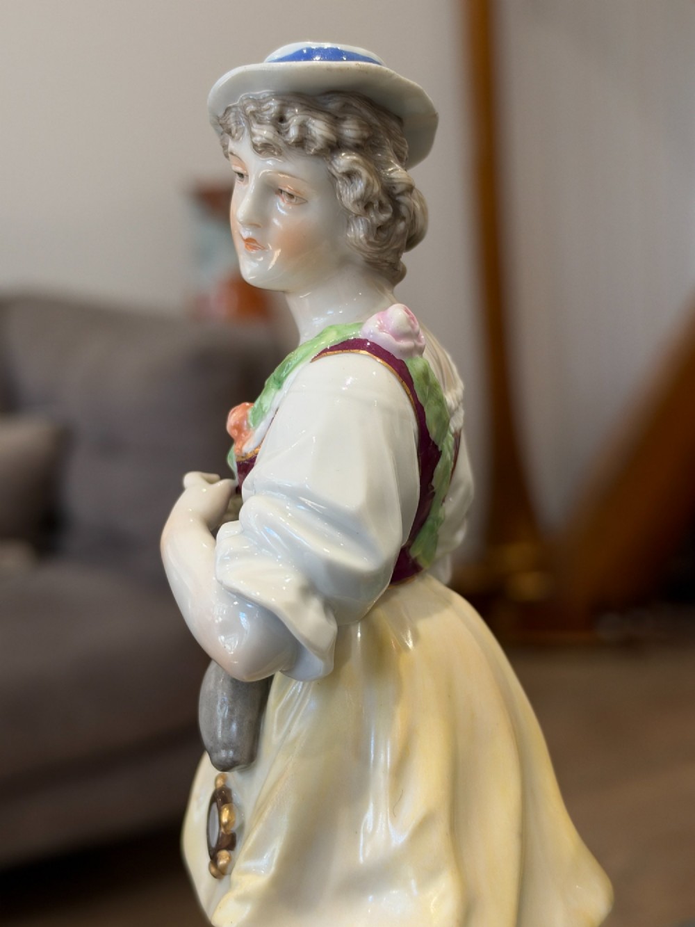 A pair of antique hand-painted German porcelain figures depicting a shepherdess with a lamb and a shepherd holding a basket, set on circular gilded bases. View VIII