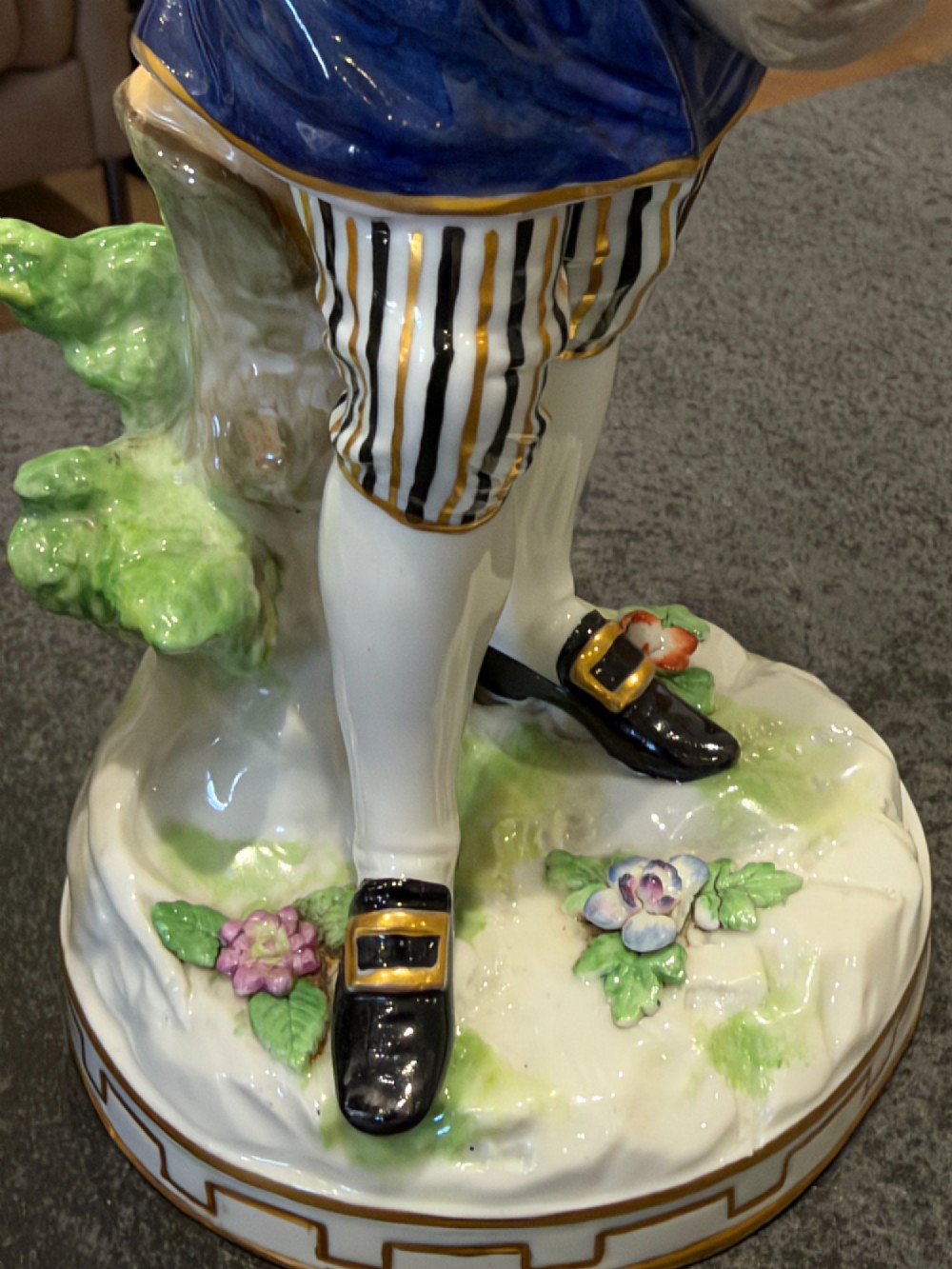 A pair of antique hand-painted German porcelain figures depicting a shepherdess with a lamb and a shepherd holding a basket, set on circular gilded bases. View IX