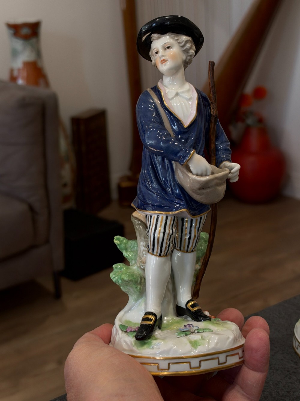 A pair of antique hand-painted German porcelain figures depicting a shepherdess with a lamb and a shepherd holding a basket, set on circular gilded bases. View XIII