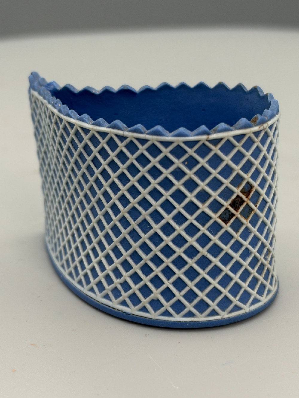 An eighteenth-century curved blue jasperware ceramic vessel decorated with a white lattice pattern and a serrated rim. View III