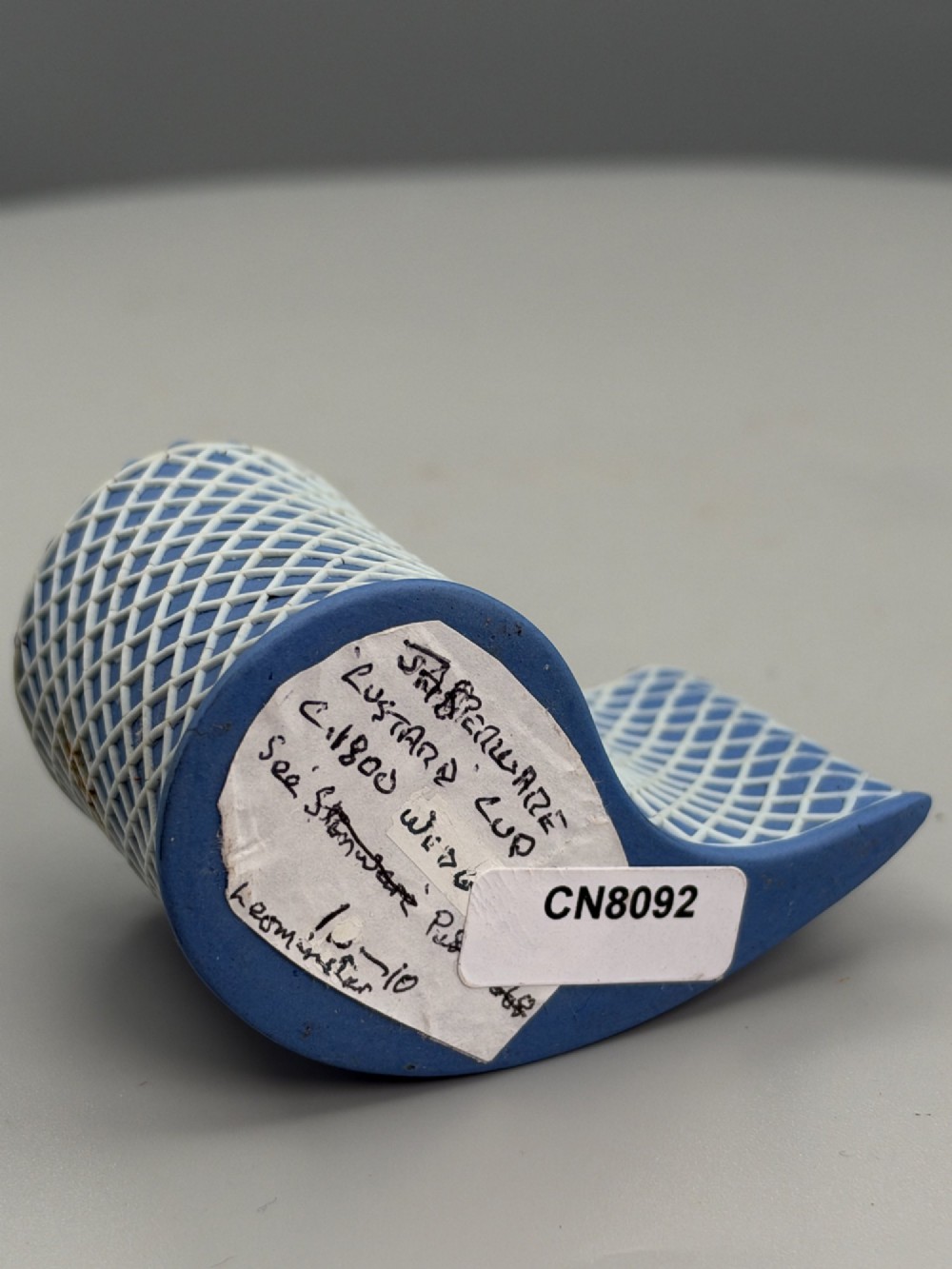 An eighteenth-century curved blue jasperware ceramic vessel decorated with a white lattice pattern and a serrated rim. View VI