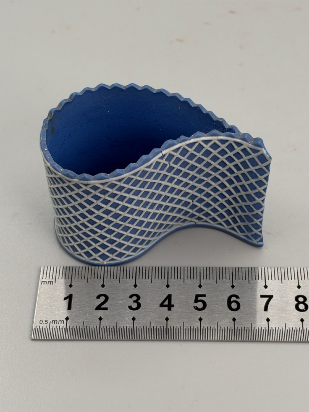 An eighteenth-century curved blue jasperware ceramic vessel decorated with a white lattice pattern and a serrated rim. View VII