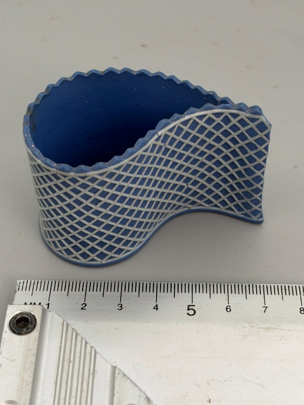 An eighteenth-century curved blue jasperware ceramic vessel decorated with a white lattice pattern and a serrated rim. View VIII