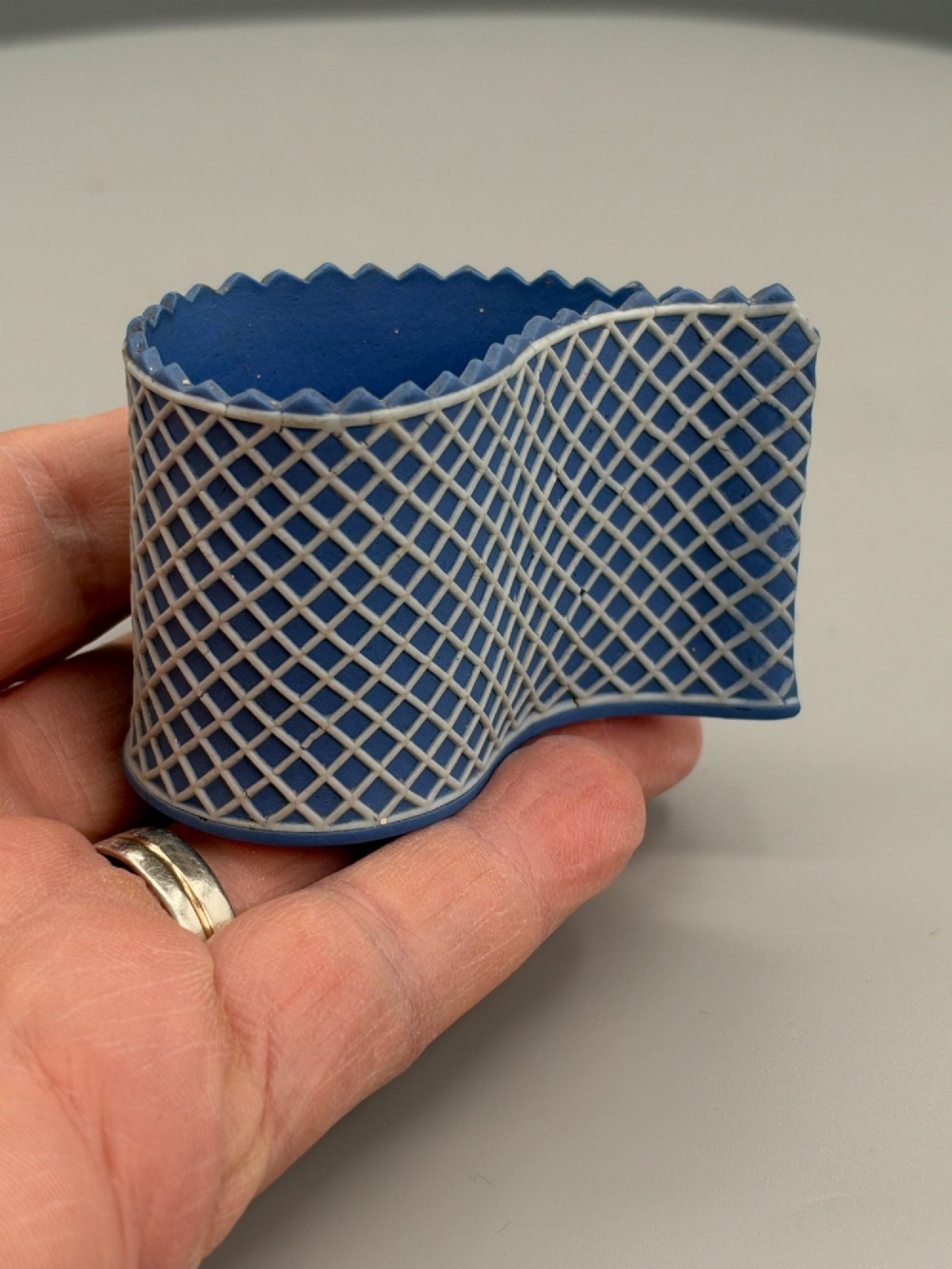 An eighteenth-century curved blue jasperware ceramic vessel decorated with a white lattice pattern and a serrated rim. View IX