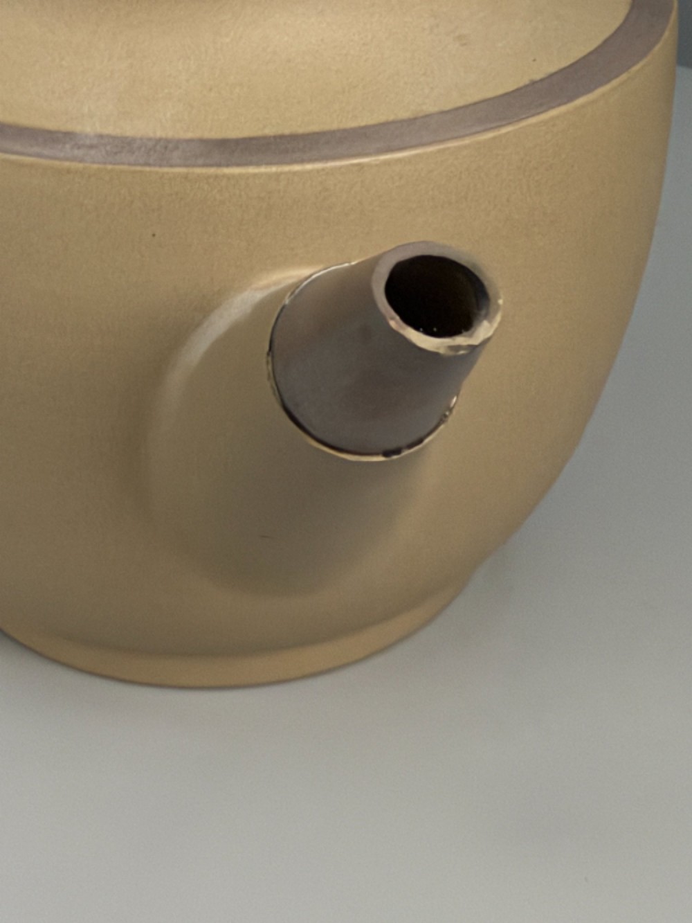 An 18th-century unglazed buff stoneware teapot with dark brown rim bands, a curved handle, and a round lid finial. View XIII