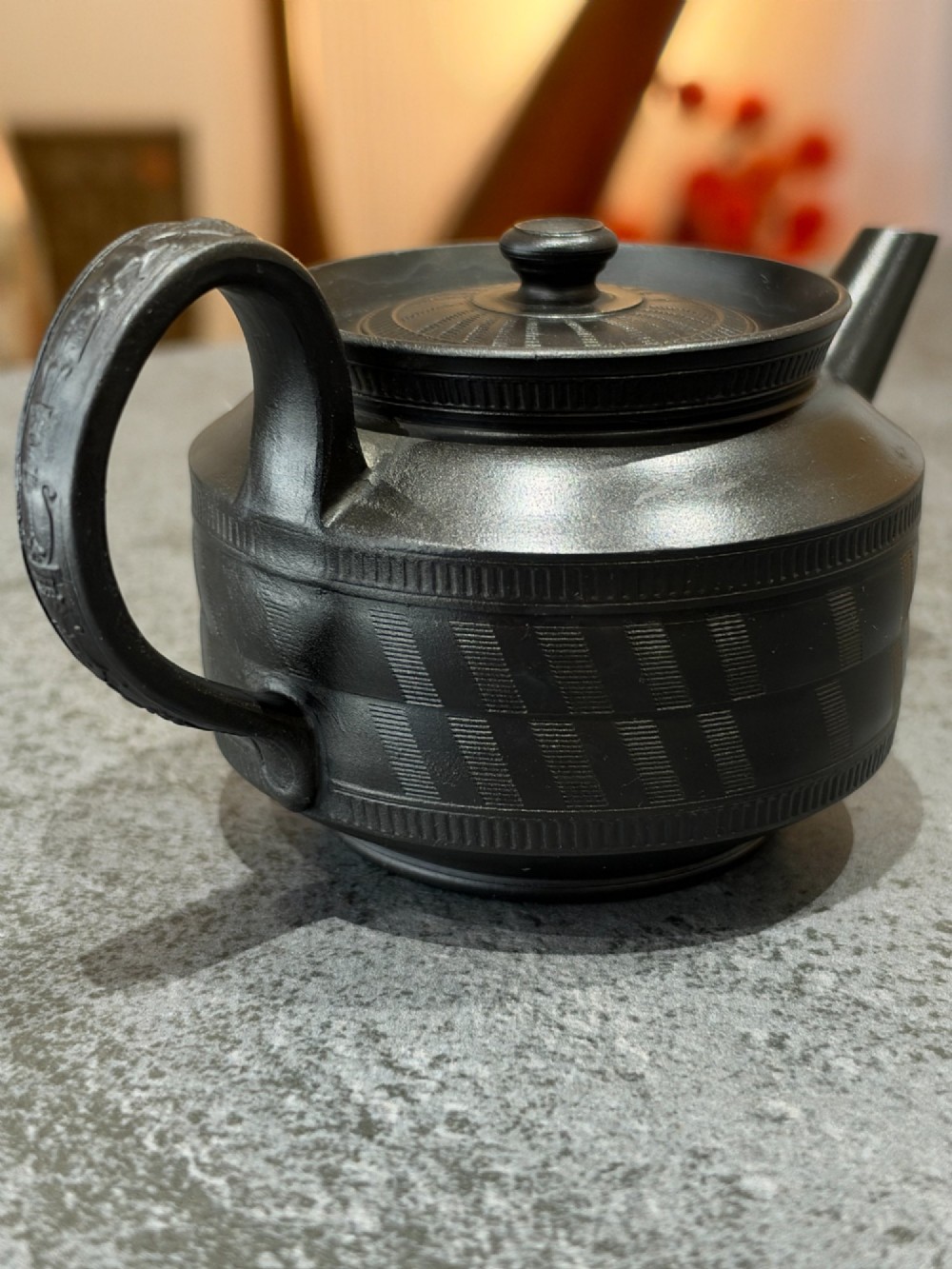 A matte black Georgian basalt stoneware teapot featuring engine-turned geometric band pattern detail and a decorative moulded handle. View II
