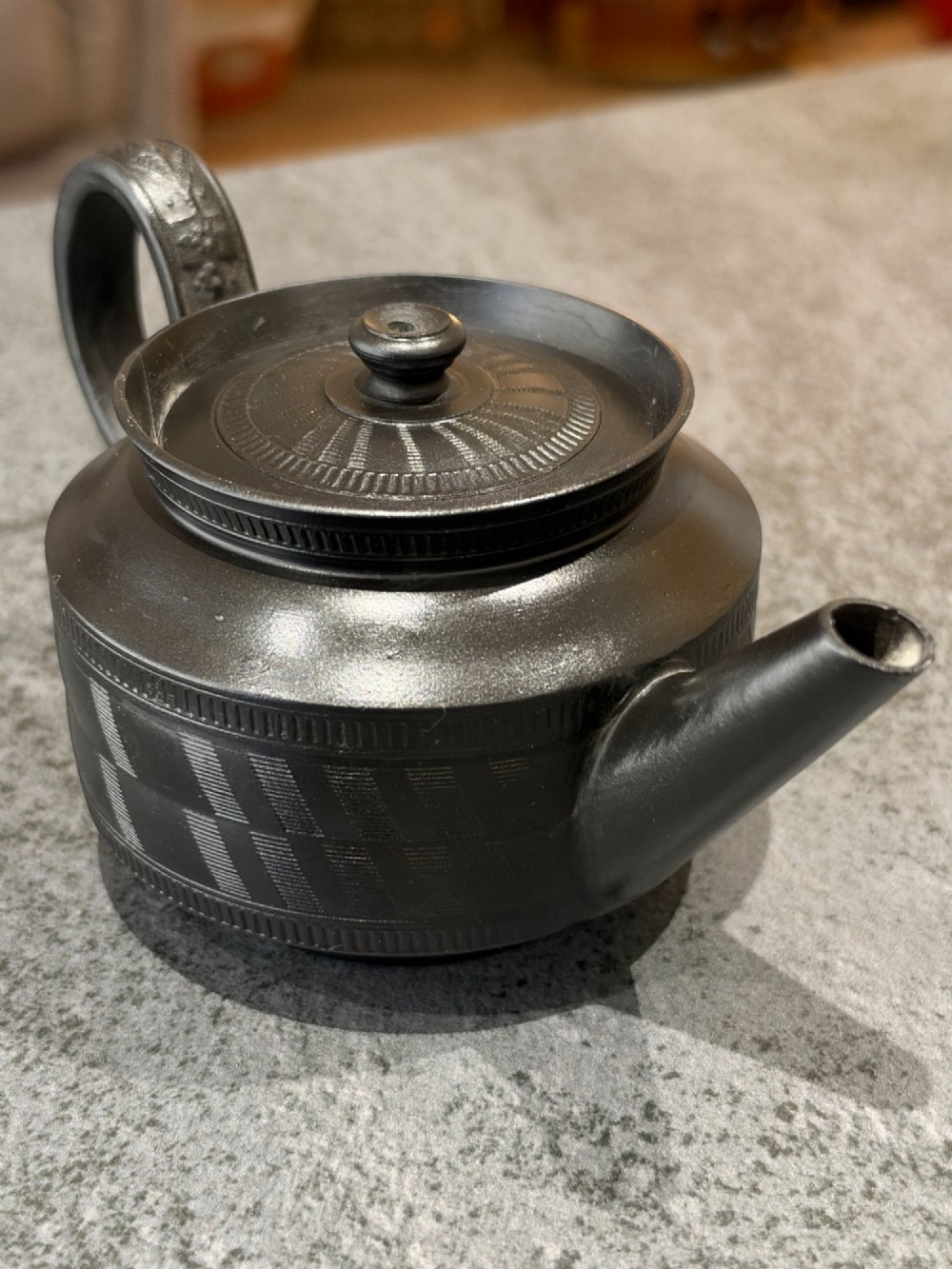 A matte black Georgian basalt stoneware teapot featuring engine-turned geometric band pattern detail and a decorative moulded handle. View III