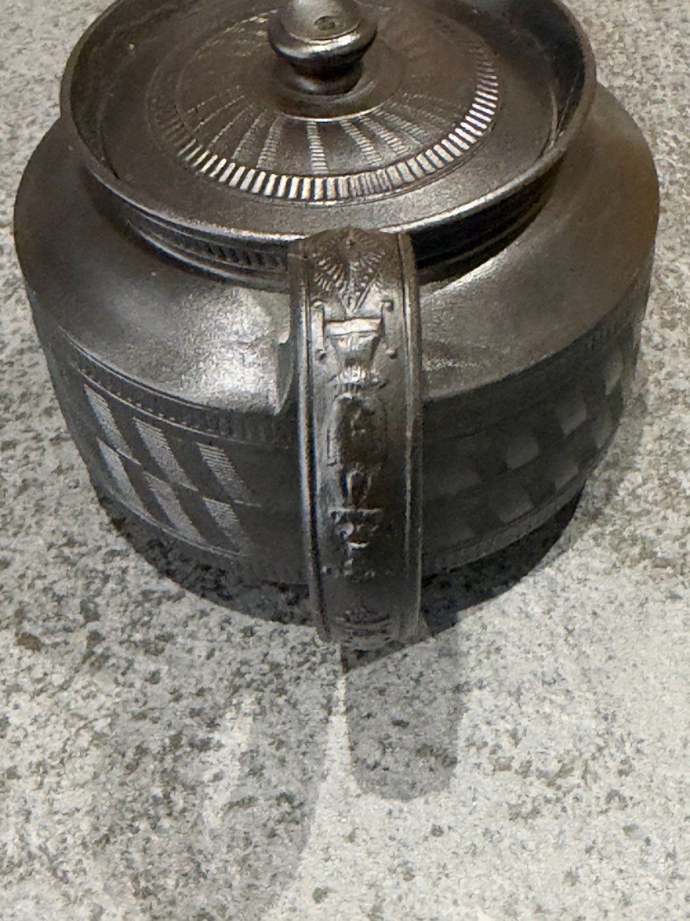 A matte black Georgian basalt stoneware teapot featuring engine-turned geometric band pattern detail and a decorative moulded handle. View VI