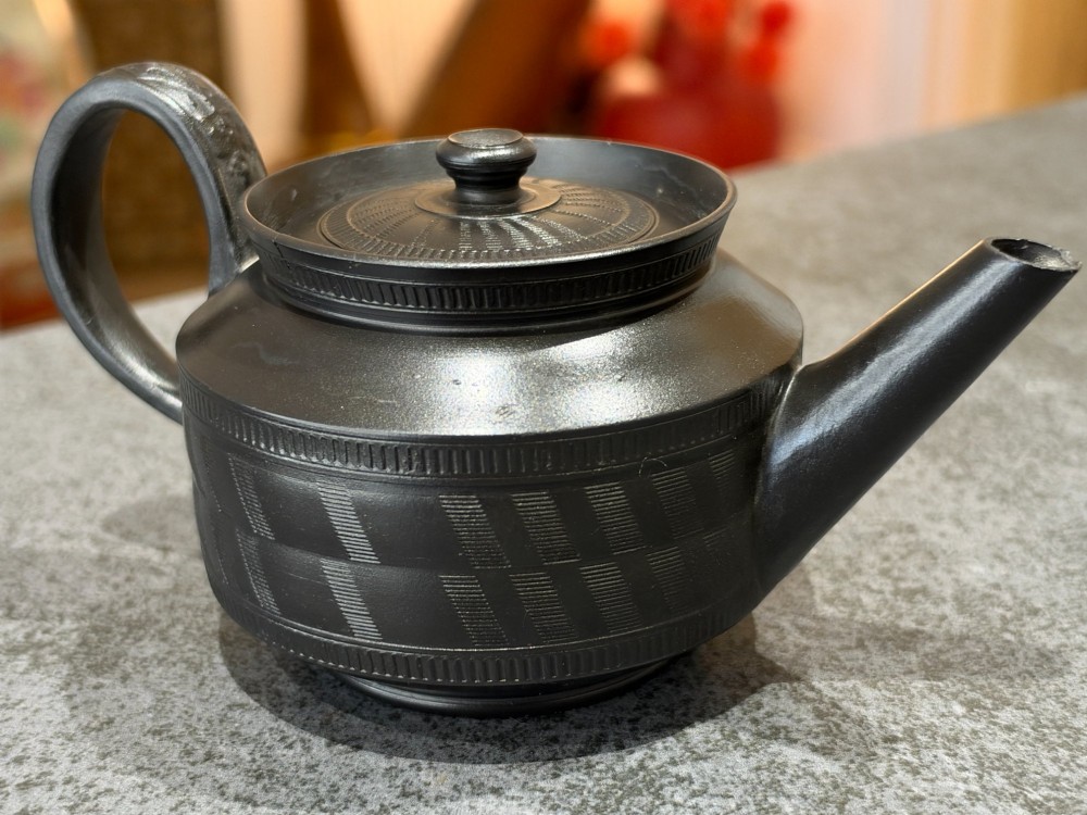 A matte black Georgian basalt stoneware teapot featuring engine-turned geometric band pattern detail and a decorative moulded handle. View IX