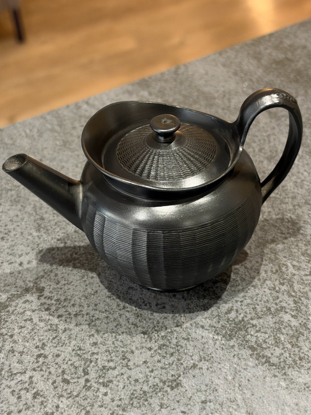A small Georgian black basalt ware teapot featuring a ribbed pattern on the lower body, an arched handle, and a matching lid with a knob finial. View II