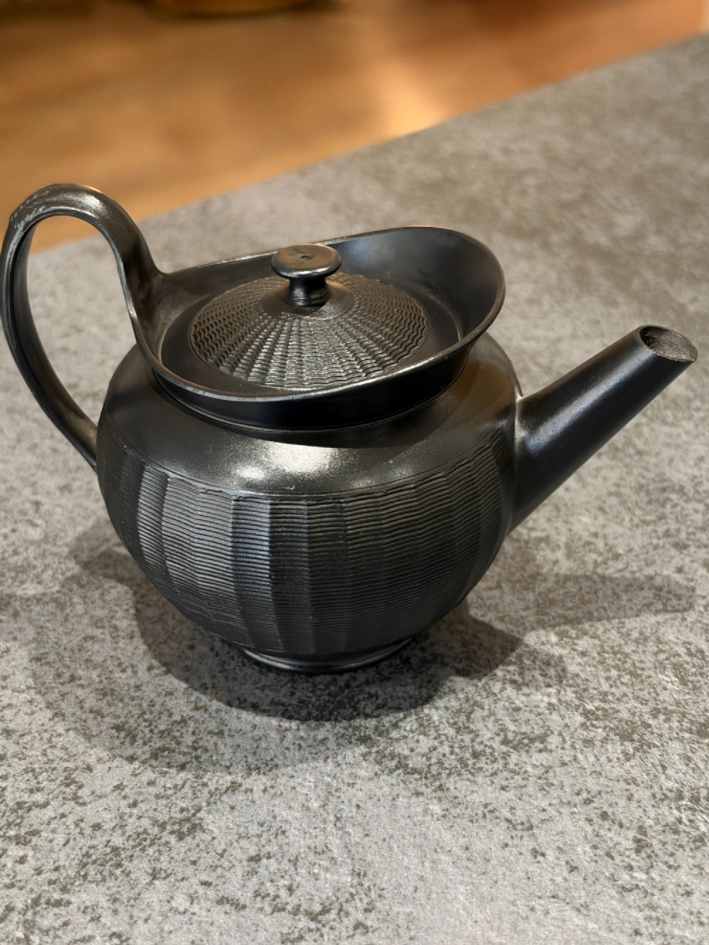 A small Georgian black basalt ware teapot featuring a ribbed pattern on the lower body, an arched handle, and a matching lid with a knob finial. View III