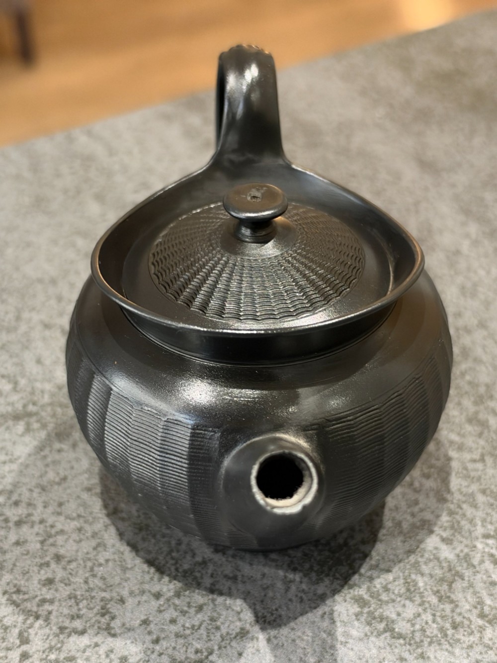 A small Georgian black basalt ware teapot featuring a ribbed pattern on the lower body, an arched handle, and a matching lid with a knob finial. View IV