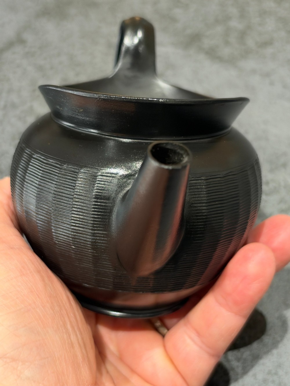 A small Georgian black basalt ware teapot featuring a ribbed pattern on the lower body, an arched handle, and a matching lid with a knob finial. View VII