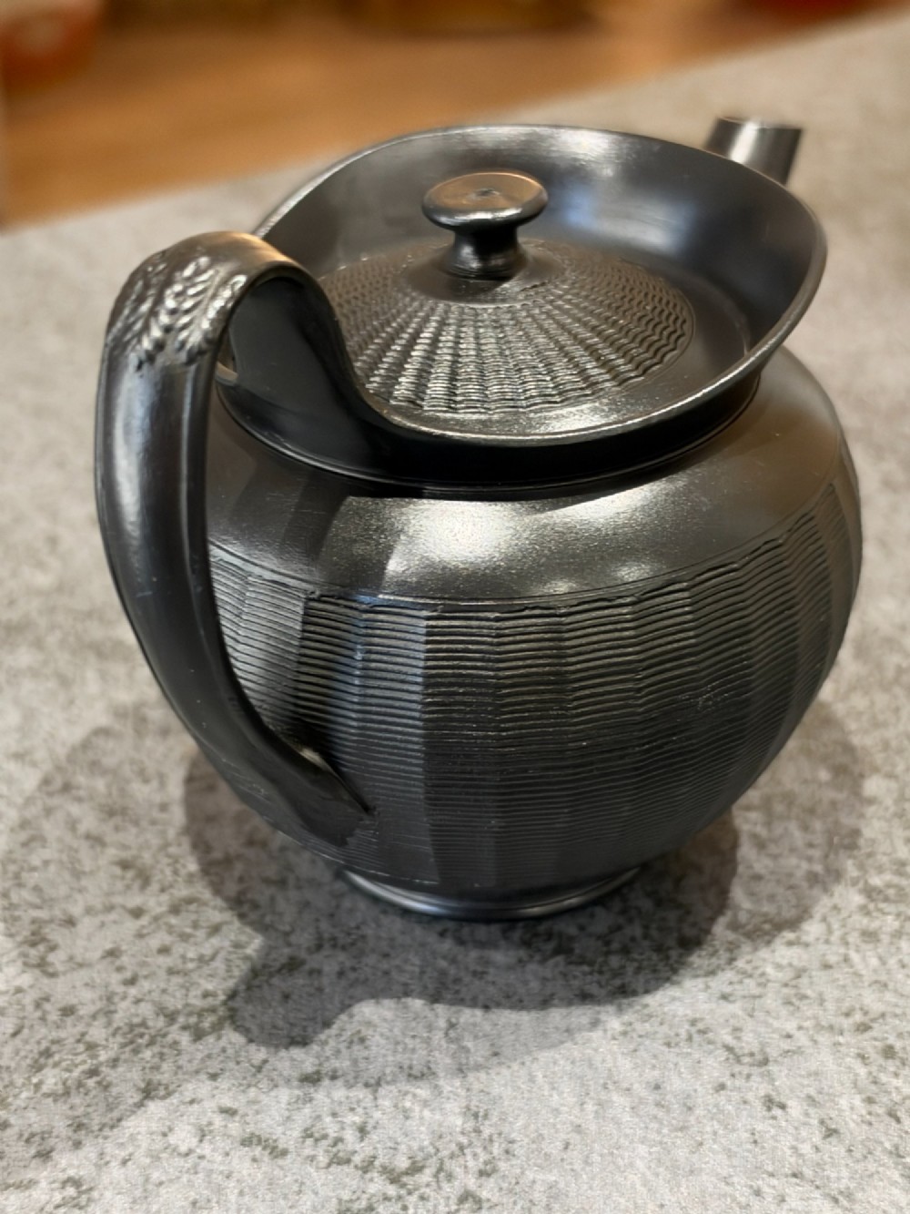 A small Georgian black basalt ware teapot featuring a ribbed pattern on the lower body, an arched handle, and a matching lid with a knob finial. View VIII