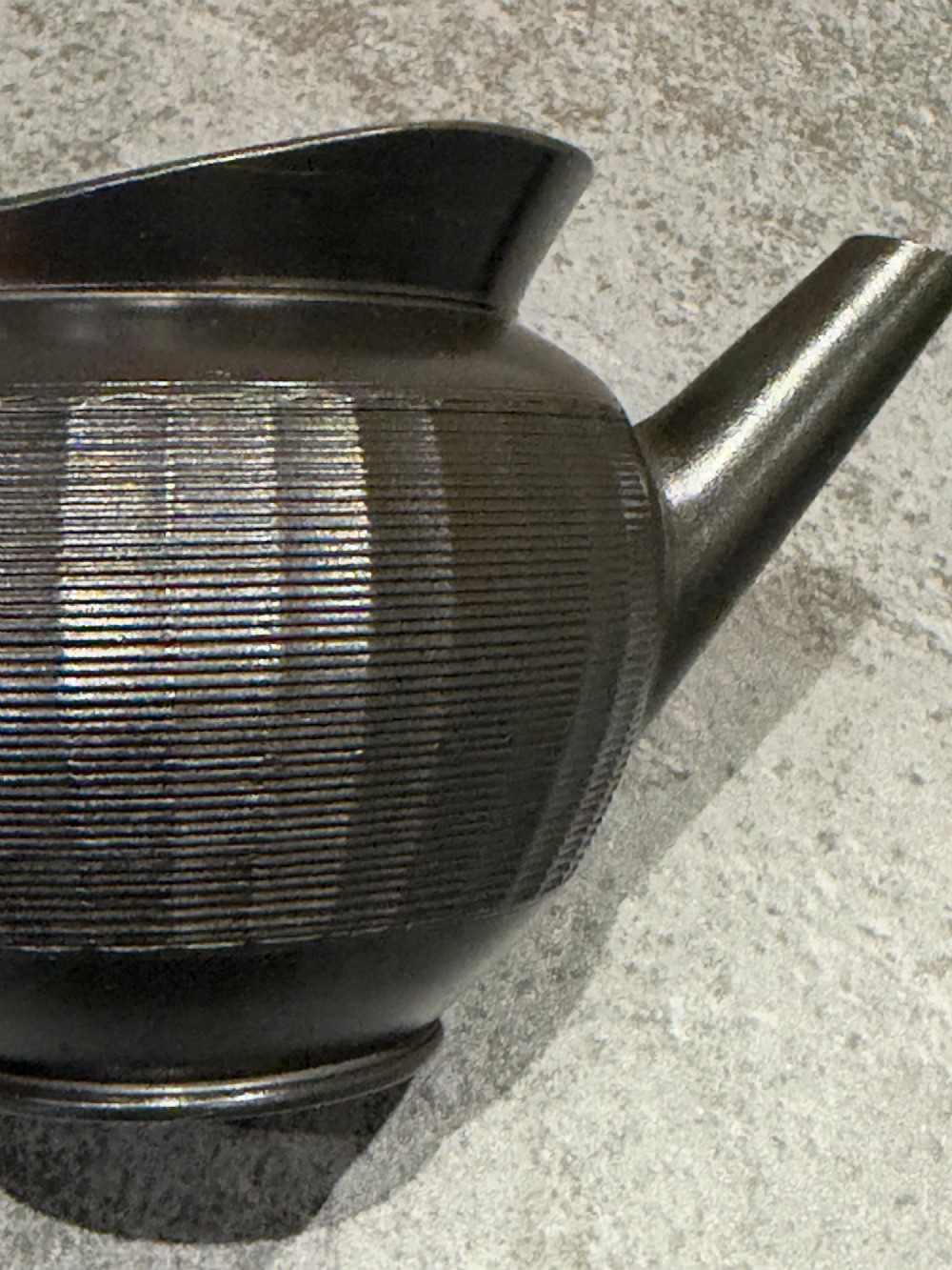 A small Georgian black basalt ware teapot featuring a ribbed pattern on the lower body, an arched handle, and a matching lid with a knob finial. View IX