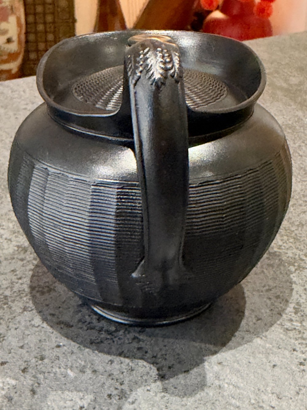 A small Georgian black basalt ware teapot featuring a ribbed pattern on the lower body, an arched handle, and a matching lid with a knob finial. View XI