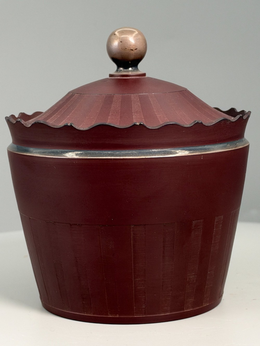 An 18th-century terracotta-coloured red stoneware sugar basin and lid with engine-turned vertical fluting and a metal ball finial.