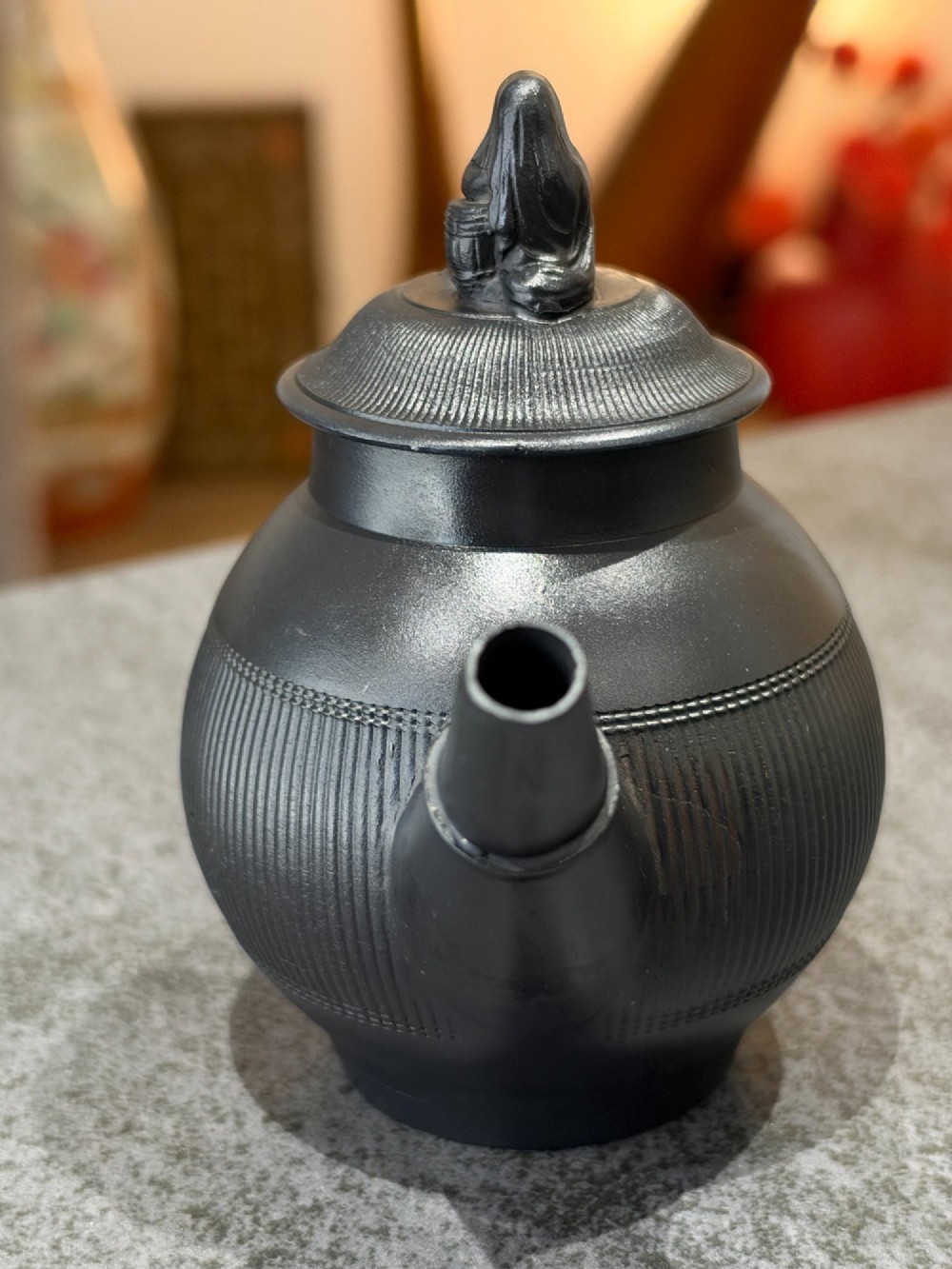 An antique matte black basalt teapot featuring an engine-turned ribbed body, a fitted lid with a figural knop, and a curved handle. View VII